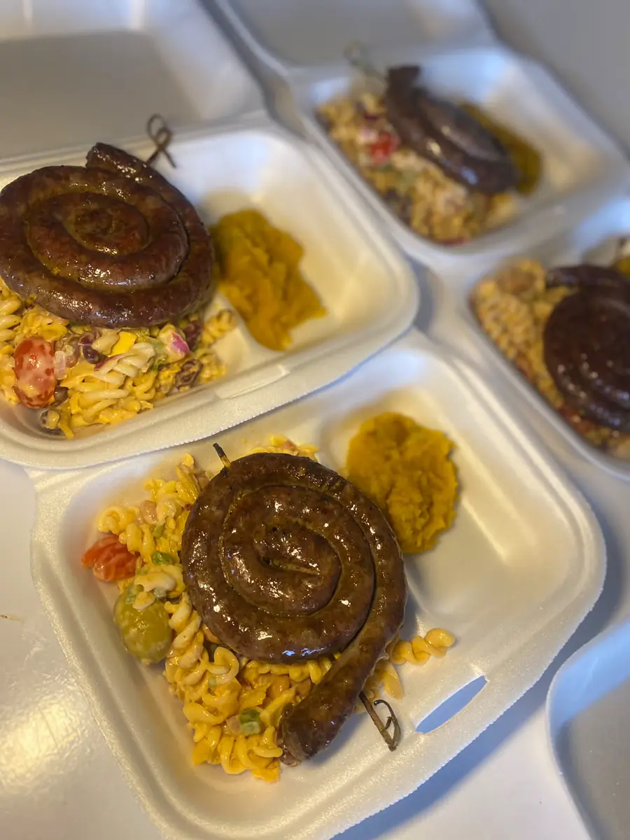 Compartmented meal trays with sausages, pasta salad, and sides