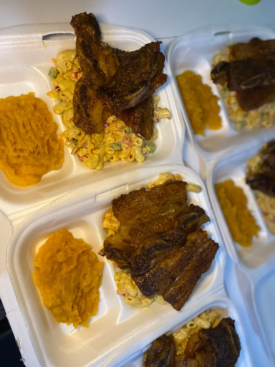 Takeout trays with ribs, macaroni salad, and side dishes