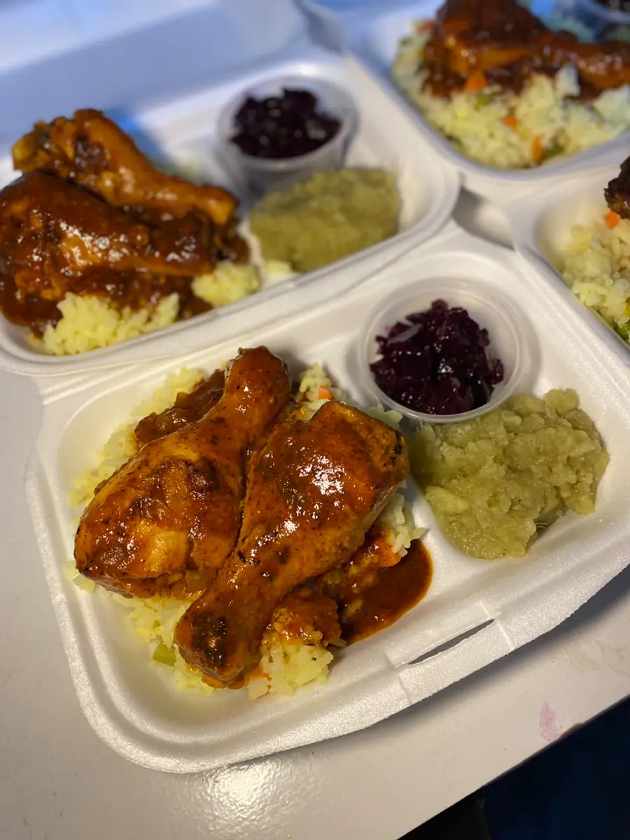Takeout trays of glazed roasted chicken with yellow rice and sides